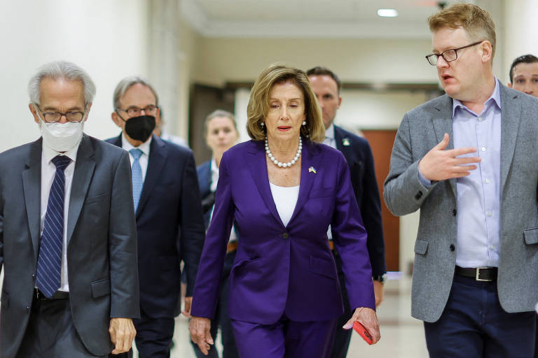 Quatro homens caminham ao lado de Nancy Pelosi, no centro