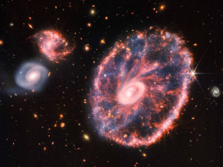 Imagem de infravermelho feita pelo Telescópio Espacial James Webb mostra a galáxia Roda de Carro e outras duas menores ao fundo