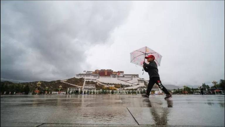 Menino caminha com um guarda-chuva em um dia nublado