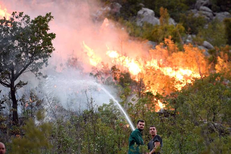 Voluntários tentam apagar chamas em planície