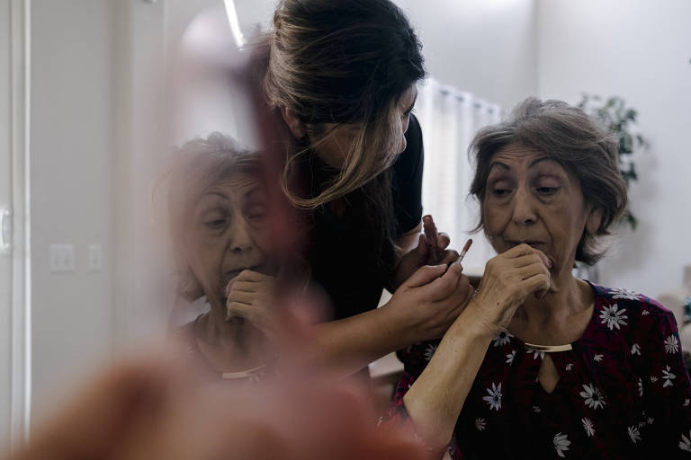 Uma mulher idosa sendo cuidada pela filha