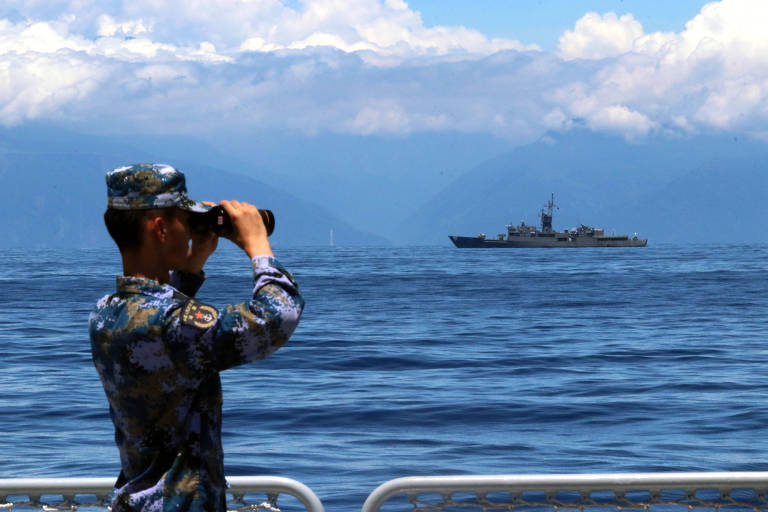 Soldado usa binóculo pra enxergar exercícios militares conduzidos pela marinha da China ao redor de Taiwan
