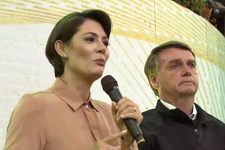 De pé, a primeira-dama Michelle Bolsonaro discursa ao lado do presidente Jair Bolsonaro em culto evangélico em Belo Horizonte