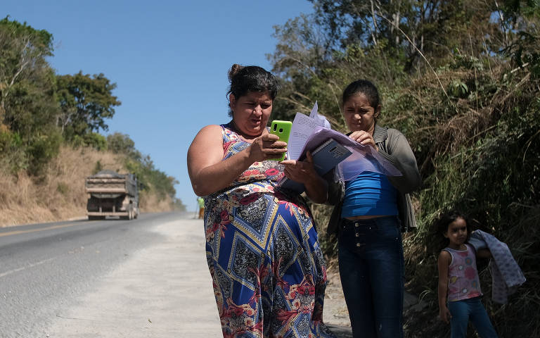 Juliane do Carmo Ferreira e sua filha Ana Júlia fazem tarefas da escola da adolescente na estrada, que é o único local próximo de sua casa com pega sinal de celular; elas moram na zona rural da Fercal, região do DF