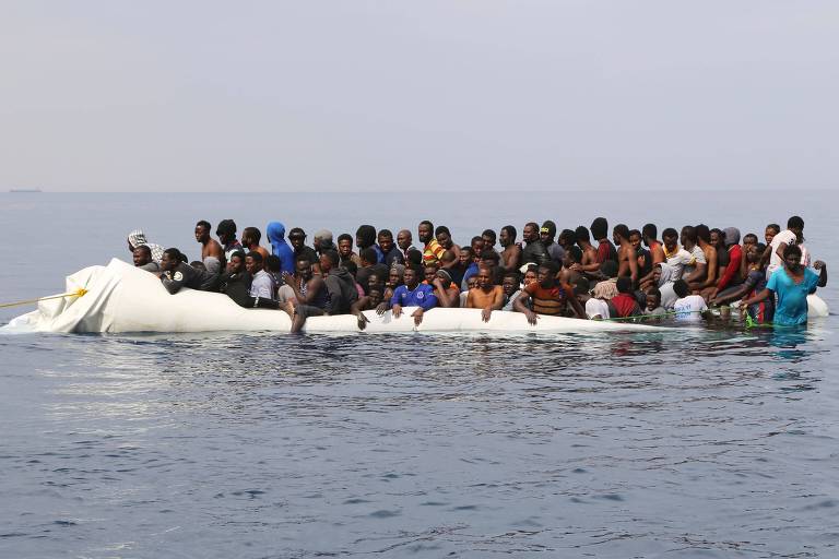 Foto de 2017 mostra migrantes líbios esperando para serem resgatados após o barco inflável em que estavam tentando atravessar o mar Mediterrâneo para chegar à Europa furar