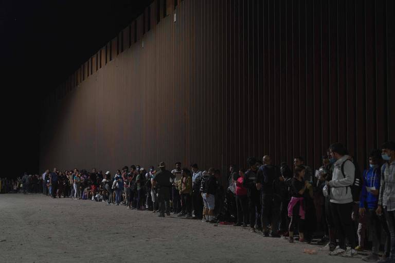 Presos pela polícia dos Estados Unidos ao atravessarem a fronteira do México para Yuma, no Arizona, migrantes aguardam para serem registrados pela patrulha norte-americana
