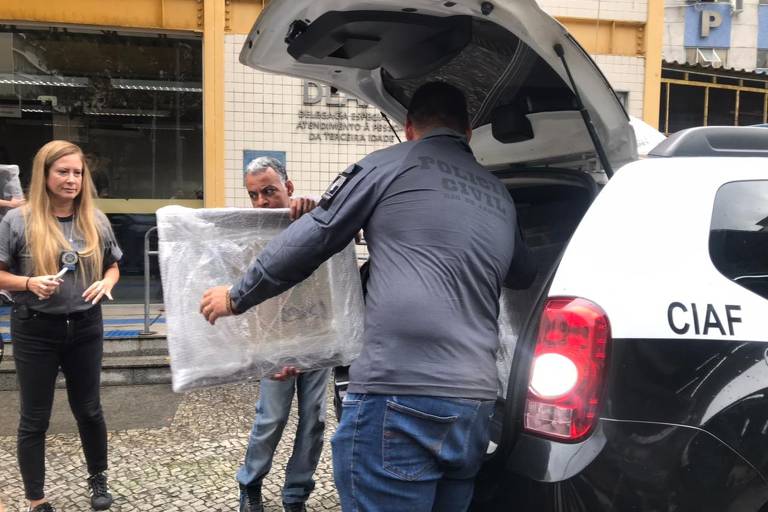 policiais retiram quadro embalado de plástico de viatura de policia