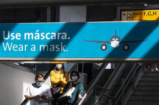 ***Especial  30 anos de Privatizacoes.: Painel  com alerta para usar mascaras afixados sobre escada rolante no Terminal 3 do Aeroporto Internacional de Cumbica