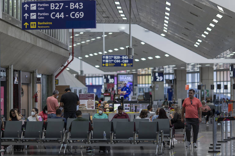 Imagem do aeroporto Galeão, no Rio. Pessoas estão sentadas em cadeiras da área doméstica.