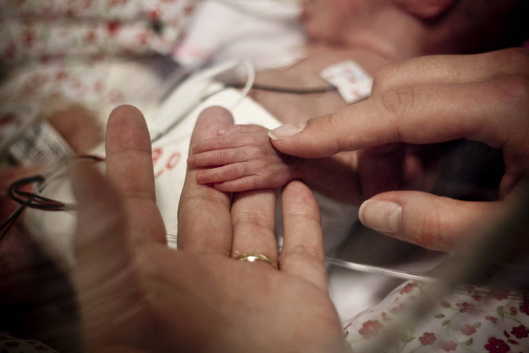 Mãe segura em seus dedos a mão de recém-nascido