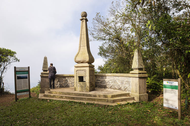 foto de um monumento pontudo localizado próximo a um mirante a céu aberto, numa região de mata