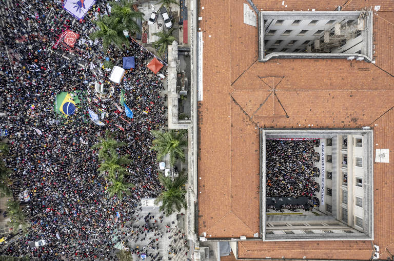 Imagem aérea de dentro do pátio das Arcadas e na parte externa mostra grupo de pessoas aglomeradas