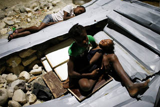 Children sleep over metal sheets in a partially destroyed school used as a shelter after Hurricane Matthew hit Jeremie