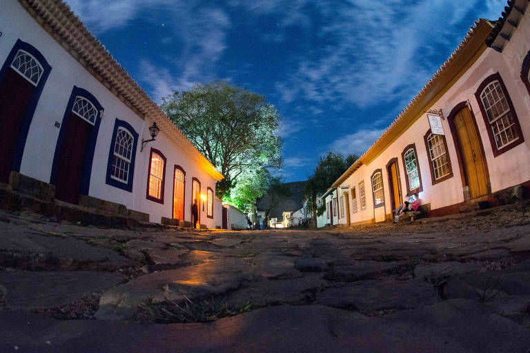 A foto mostra uma rua de Tiradentes ao entardecer, com casas em estilo colonial