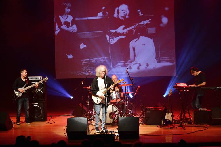 Em foto colorida, o compositor e guitarrista Tony Babalu aparece em um palco tocando com sua banda
