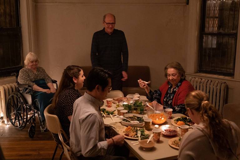 Cinema de filme representando uma mesa de jantar com três mulheres e um homem sentandos, tendo outro homem, na posição da cabeceira, em pé