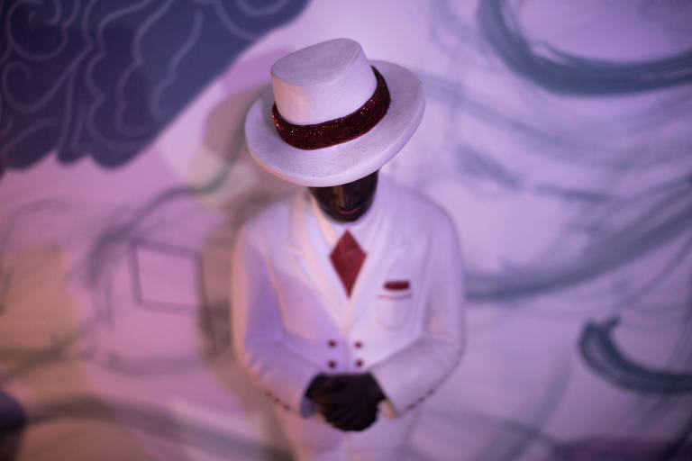 Boneco de homem negro com terno branco, gravata vermelha e chapéu branco