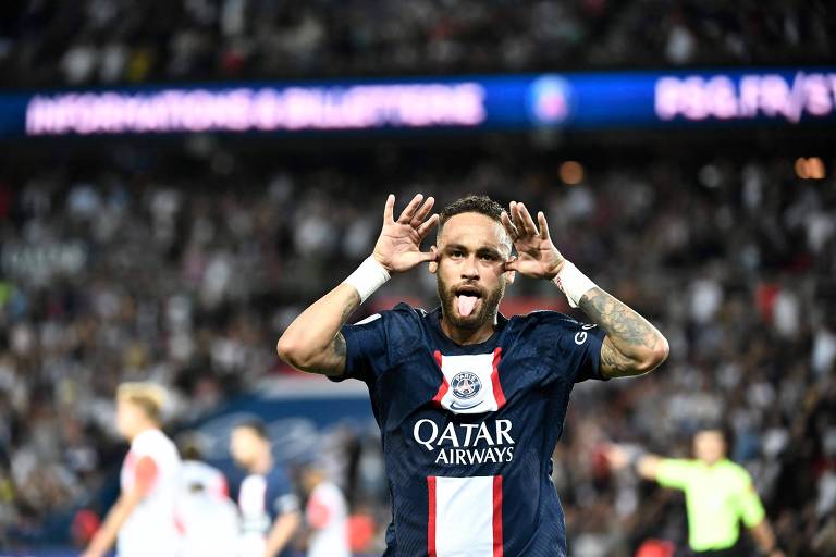 Neymar aparece no campo, olhando para a câmera e comemorando o gol mostrando a língua e as mãos no rosto