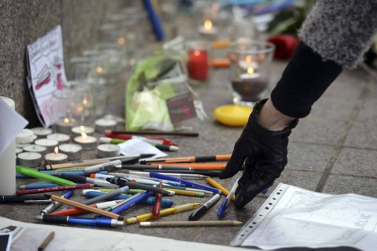 Mulher coloca uma caneta na praça central da cidade de Estrasburgo, no leste da França, em 8 de janeiro de 2015, para homenagear as vítimas de um ataque de homens armados contra o jornal satírico francês Charlie Hebdo, em Paris, no dia anterior, que deixou pelo menos 12 mortos e muitos outros feridos