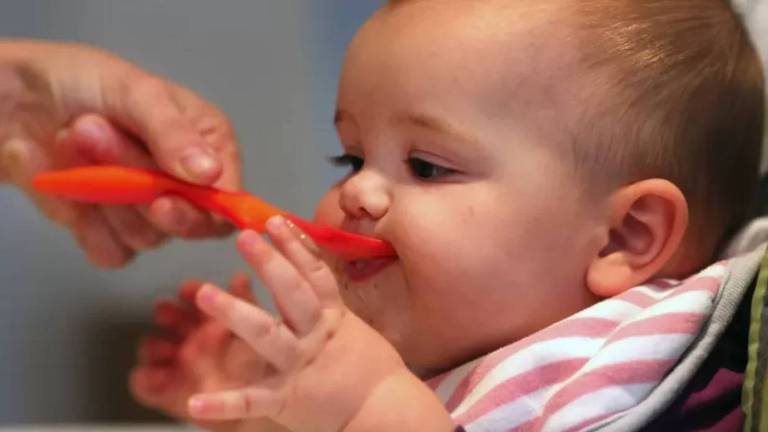 Bebê recebe alimento na boca com uma colher