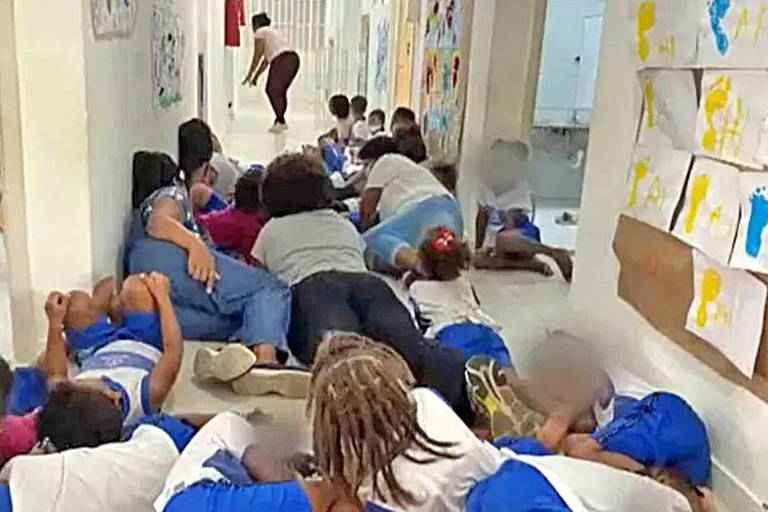 Crianças e adultos deitados no chão em um corredor