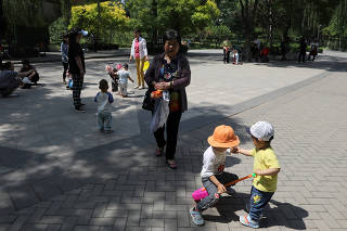 FILE PHOTO: Children play next to adults at a park in Beijing
