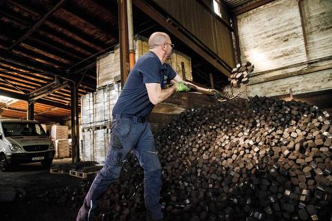 A worker loads briquettes of coal in the storage of the 