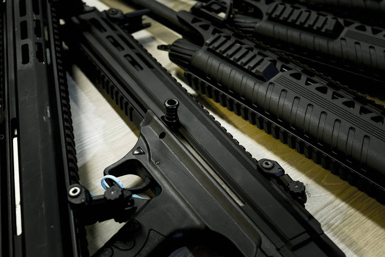 Imagem mostra armas de fogo sobre uma mesa.