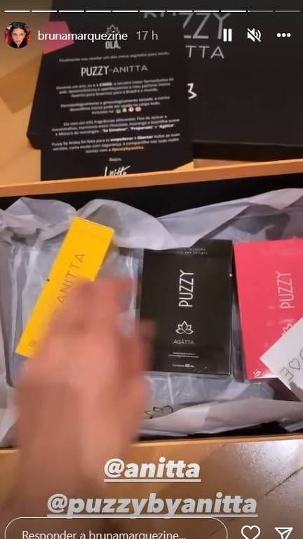 Em foto colorida, mulher abre caixa e exibe vários frascos de perfumes