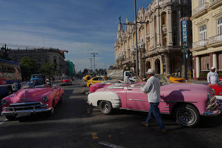 Drivers of vintage cars wait for tourists in downtown Havana