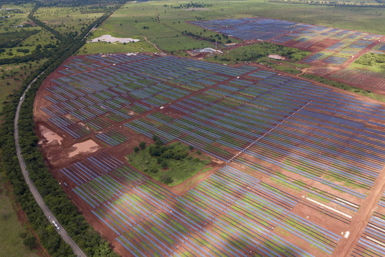 Imagem mostra diversas placas solares em uma fazenda de produção de energia solar em Minas