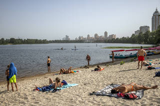 Local residents relax on a sand beach on the Dnipro River in Kyiv, Ukraine, on Monday, Aug. 22. 2022. (Jim Huylebroek/The New York Times)