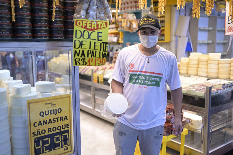 A foto mostra o gerente de loja no Mercado Central, Wellington Silva, que mostra nas mãos um queijo Canastra.