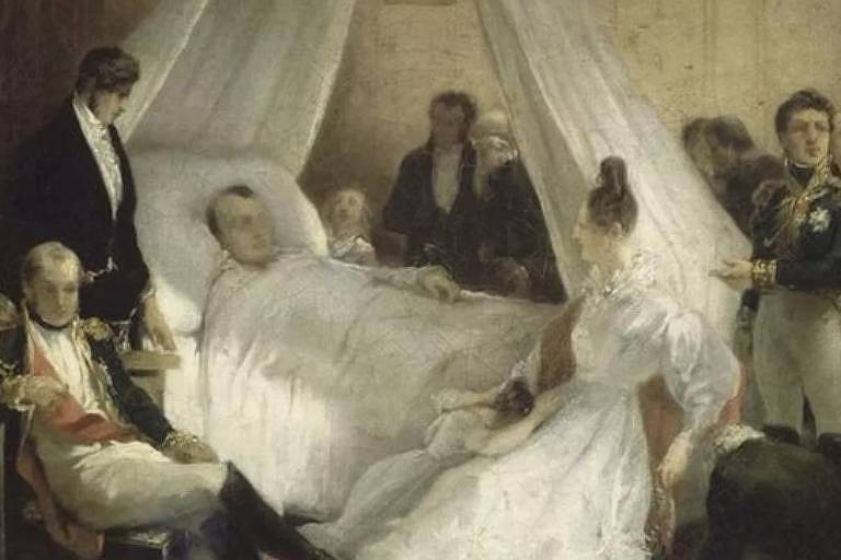 Em foto, homem aparece deitado em uma cama cercado por várias pessoas