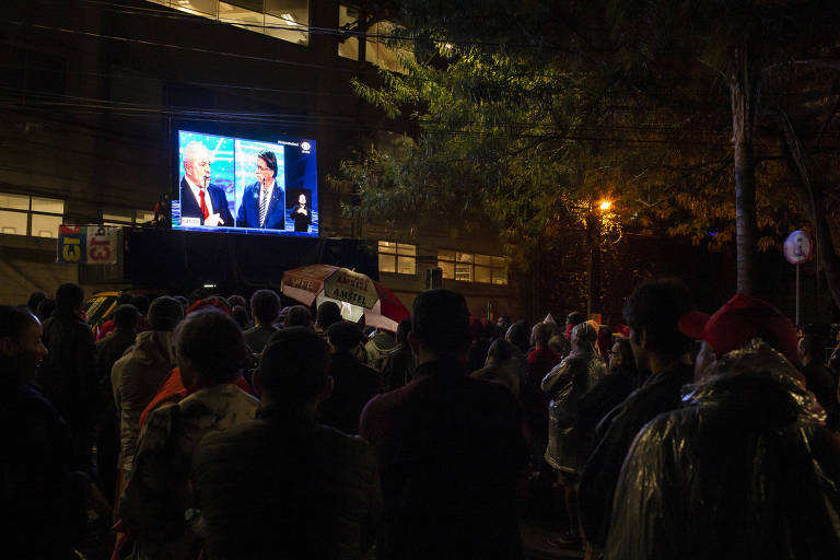 Público acompanha pelo telão, do lado de fora da Rede Bandeirantes, o debate entre os candidatos à presidência da república na noite deste domingo (28)