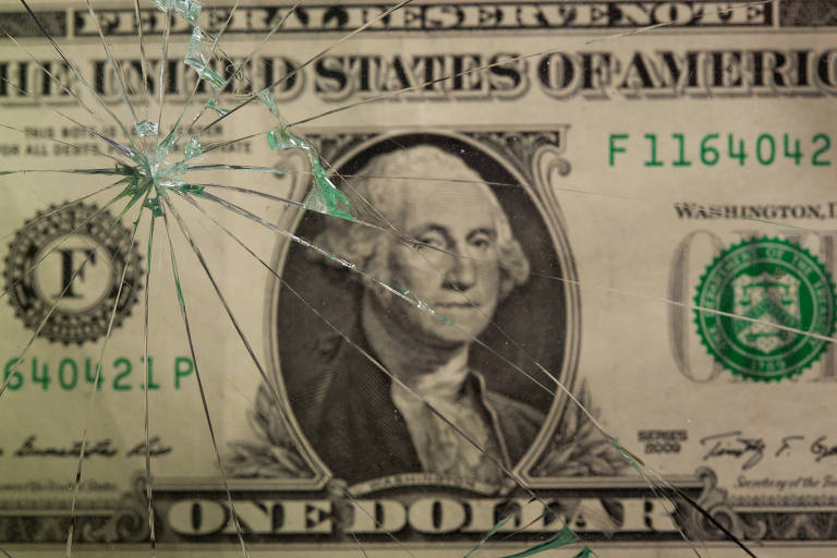Nota de dólar americano vista através de um vidro quebrado 