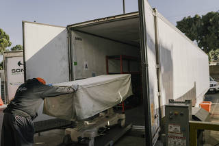 A COVID victim is transferred to a refrigerated morgue trailer outside a hospital in Los Angeles, Jan. 21, 2021.  (Isadora Kosofsky/The New York Times)