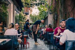 Garçom atende clientes que ficam na área externa do restaurante Sughetto Cucina