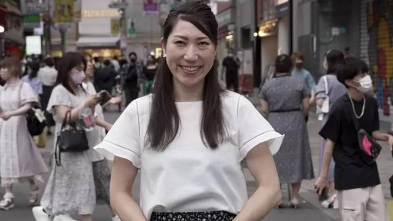 Ativista de saúde sexual Asuka Someya sorri no meio de outras pessoas na rua