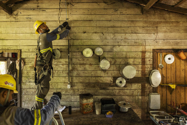 Operários da empresa CGB conferem a instalação elétrica na casa de Francisca de Oliveira Damião, 68, em Portel