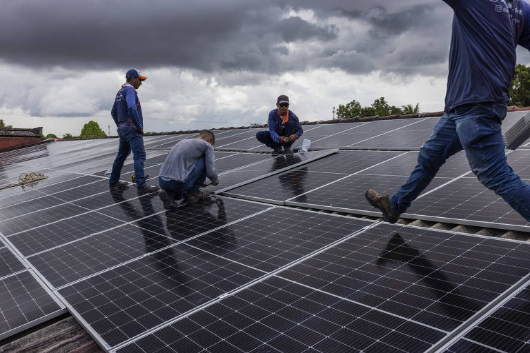 Operários instalam painéis solares fotovoltaicos em um edifício de Boa Vista (RR)