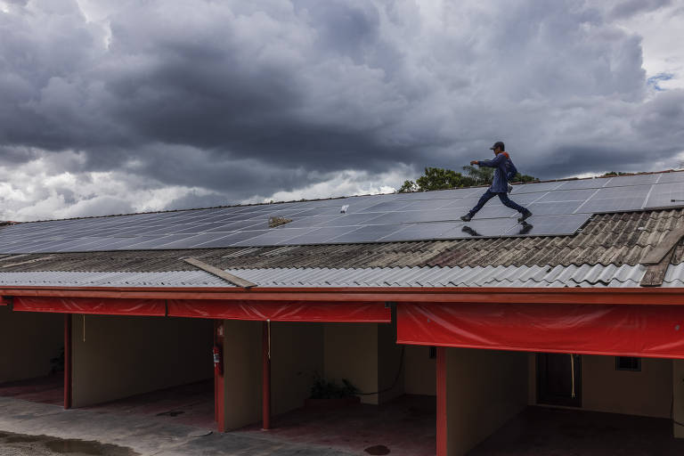 Operários instalam painéis solares fotovoltaicos no telhado de um motel na periferia de Boa Vista