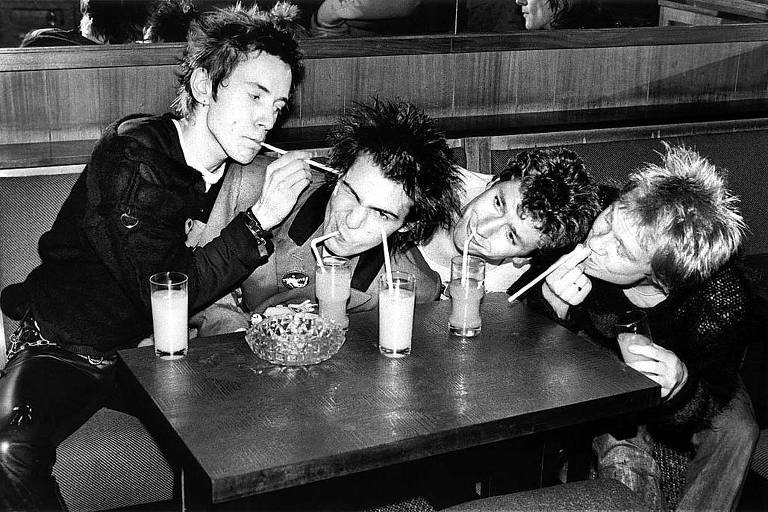 Integrantes do Sex Pistols brincam em um café em foto em preto e branco