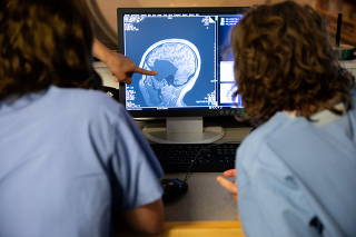 Helen Santoro, left, examines a scan of her brain with her mother at a lab at the Massachusetts Institute of Technology in Cambridge, July 13, 2022. (Kayana Szymczak/The New York Times)