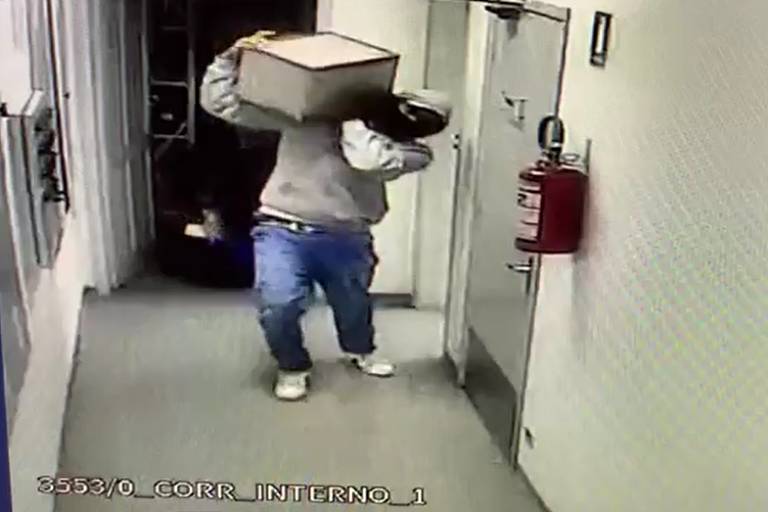 Homem carrega cofre nas costas em interior de banco