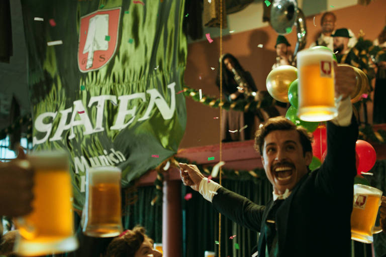 Homem ergue copo de Spaten, cerveja oficial da Oktoberfest de Blumenau, em 2022