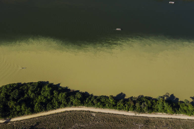Vista aérea de rio com parte da água amarela e outra verde escuro