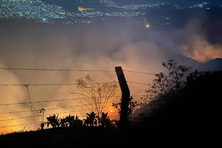 A imagem mostra fogo na Serra do Curral, cartão-postal de Belo Horizonte, com a cidade ao fundo.