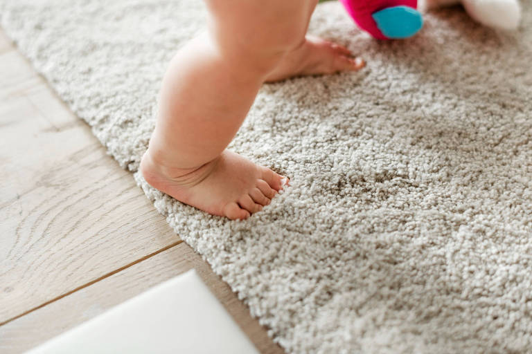 Um bebê pisa sobre um tapete