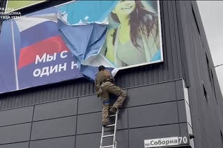 Ukrainian soldier rips down a banner, in Vovchansk